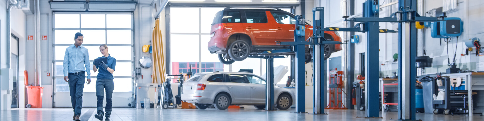 Customer and mechanic walking through automotive shop with exhaust extraction