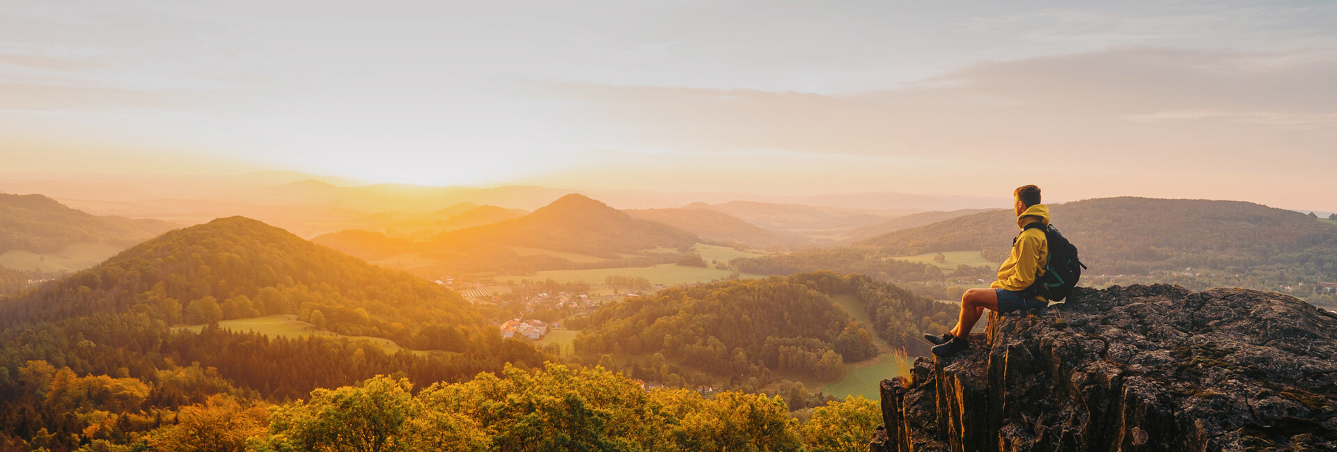 Man on a mountain looking at amazing view with sunset